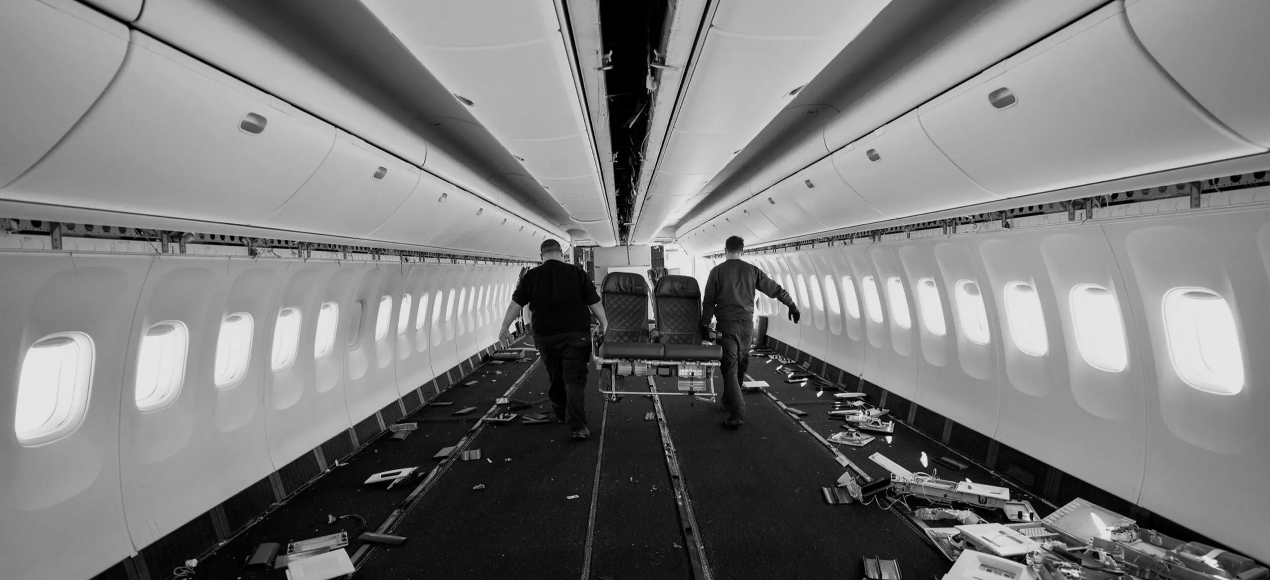Two persons carry an old AirCraft seat from a cabin